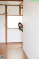 A woman standing in an empty room with a window.