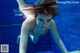 A woman in a red bikini is underwater in a pool.