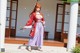 A woman in traditional Japanese attire stands on steps with cherry blossom petals.