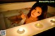 A woman laying in a bathtub with candles in it.