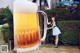 A woman standing next to a giant mug of beer.