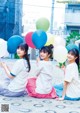 A group of young women sitting on the ground holding balloons.