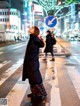 A woman standing in the middle of a crosswalk at night.